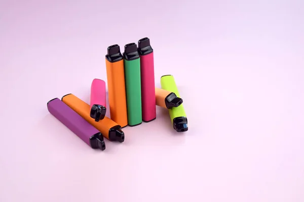 stock image Set of multicolor disposable electronic cigarettes on a pink background. The concept of modern smoking, vaping and nicotine.