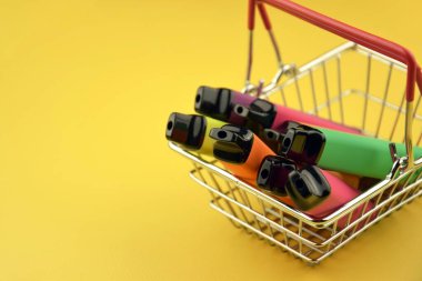 Sarı arka planda tek kullanımlık elektronik sigara seti. Modern sigara, buhar ve nikotin konsepti.