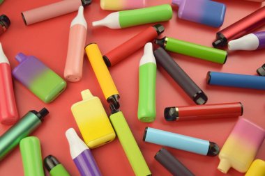 Kırmızı arka planda tek kullanımlık elektronik sigara seti. Modern sigara, buhar ve nikotin konsepti.