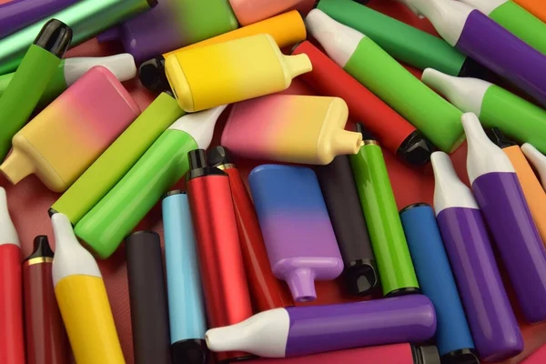 Kırmızı arka planda tek kullanımlık elektronik sigara seti. Modern sigara, buhar ve nikotin konsepti.