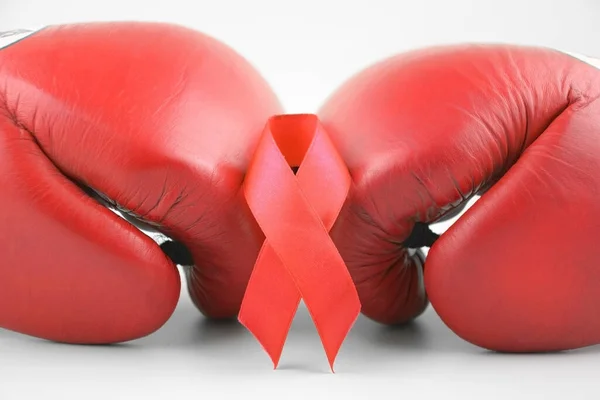 stock image Red ribbon with boxing gloves, wrestling symbol. World AIDS Day and National HIV, AIDS and Aging Awareness Month.