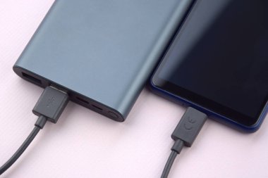 Mobil cihazları şarj etmek için güç bankası. Güç bankası olan siyah akıllı telefon şarj aleti. Mobil aygıtlar için dış pil.