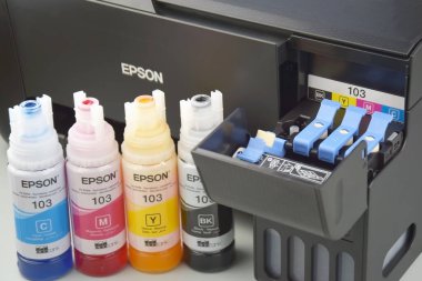 KHARKIV, UKRAINE - FEBRUARY 11, 2023: Four bottles of ink Epson, yellow, red, blue, black, built-in to the Epson L3150 series printer.