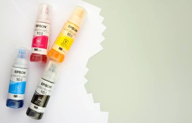 KHARKIV, UKRAINE - FEBRUARY 11, 2023: Four bottles of ink Epson, yellow, red, blue, black, built-in to the Epson L3150 series printer.