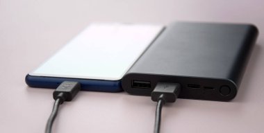 Mobil cihazları şarj etmek için güç bankası. Güç bankası olan siyah akıllı telefon şarj aleti. Mobil aygıtlar için dış pil.