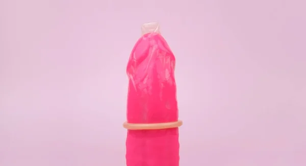 粉色背景带避孕套的粉色振动器 带有色情店的彩色文字 性健康概念 — 图库照片