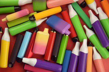 Kırmızı arka planda tek kullanımlık elektronik sigara seti. Modern sigara, buhar ve nikotin konsepti.