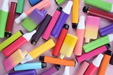 Pembe arka planda tek kullanımlık elektronik sigara seti. Modern sigara, buhar ve nikotin konsepti.