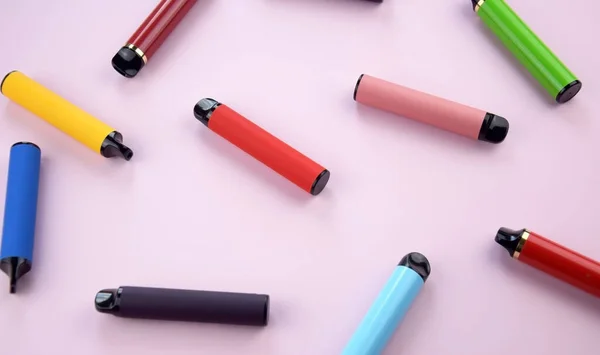 stock image Set of multicolor disposable electronic cigarettes on a pink background. The concept of modern smoking, vaping and nicotine.