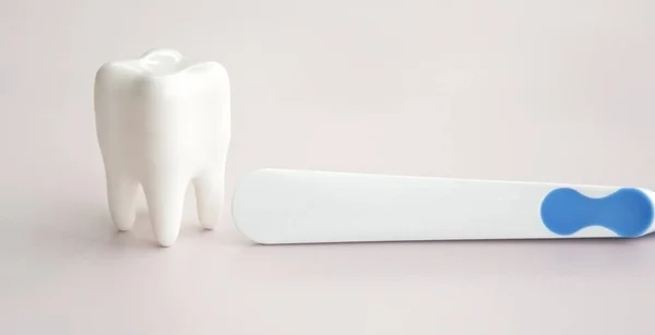 stock image Toothbrushes with a small figure of a tooth on a light background. Dental health concept.