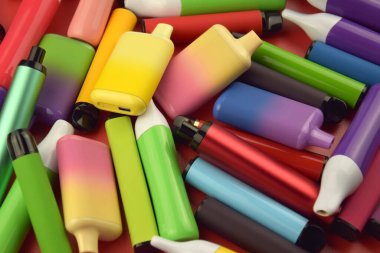 Kırmızı arka planda tek kullanımlık elektronik sigara seti. Modern sigara, buhar ve nikotin konsepti.