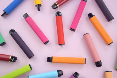 Pembe arka planda tek kullanımlık elektronik sigara seti. Modern sigara, buhar ve nikotin konsepti.