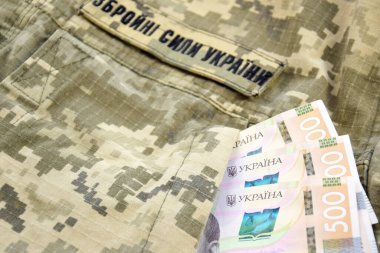 Ukrayna hrivnisi, Ukrayna silahlı kuvvetlerinin yazılı olduğu askeri bir pikselin arka planına karşı. Ücret, ödeme ve orduya bağış kavramı..