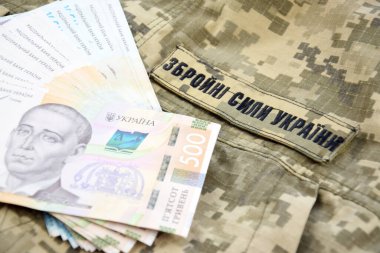 Ukrayna hrivnisi, Ukrayna silahlı kuvvetlerinin yazılı olduğu askeri bir pikselin arka planına karşı. Ücret, ödeme ve orduya bağış kavramı..