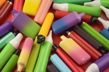 Kırmızı arka planda tek kullanımlık elektronik sigara seti. Modern sigara, buhar ve nikotin konsepti.