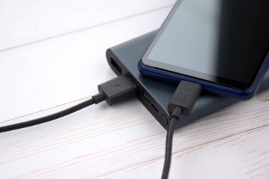 Mobil cihazları şarj etmek için güç bankası. Güç bankası olan siyah akıllı telefon şarj aleti. Mobil aygıtlar için dış pil.