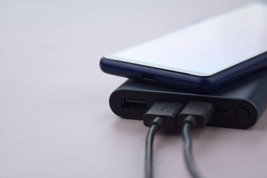 Mobil cihazları şarj etmek için güç bankası. Güç bankası olan siyah akıllı telefon şarj aleti. Mobil aygıtlar için dış pil.