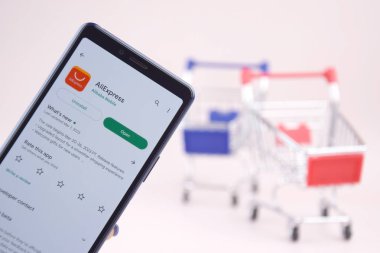 Kharkiv, Ukrayna, 31 Mart 2023: Akıllı telefonlu alışveriş arabası pembe arka planda Aliexpress logosu açtı.