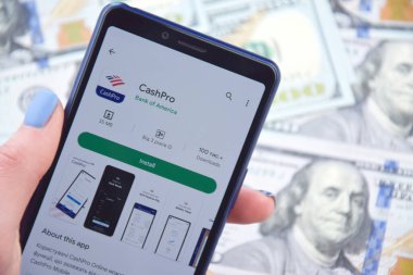 Kharkiv, Ukrayna - 13 Mart 2023: Akıllı telefon ekranında CashPro mobil bankacılık uygulaması. Amerikan dolar banknotlarının arka planı.