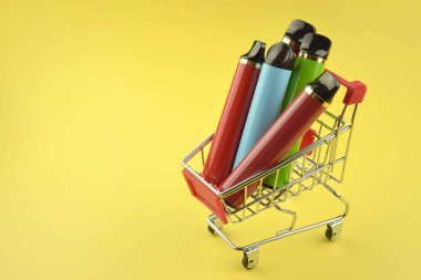 Sarı arka planda tek kullanımlık elektronik sigara seti. Modern sigara, buhar ve nikotin konsepti.