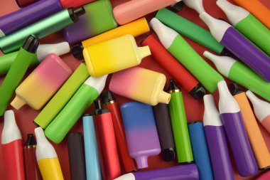 Kırmızı arka planda tek kullanımlık elektronik sigara seti. Modern sigara, buhar ve nikotin konsepti.