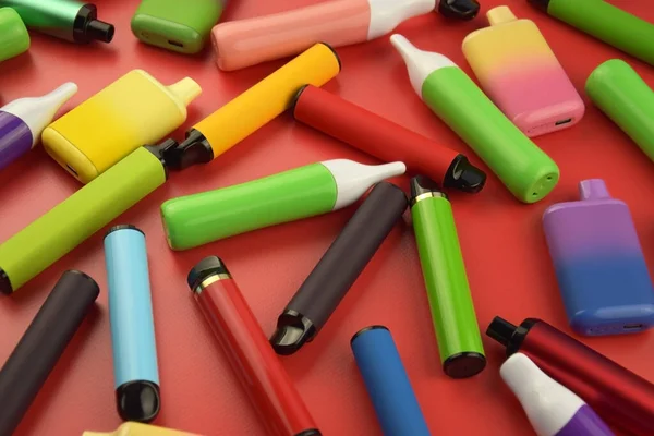 stock image Set of multicolor disposable electronic cigarettes on a red background. The concept of modern smoking, vaping and nicotine.