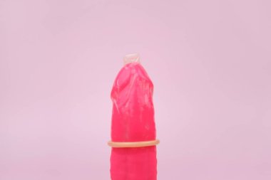 Pembe arka planda prezervatifli pembe vibratör ve seks dükkanı için metin. Seks sağlığı kavramı.
