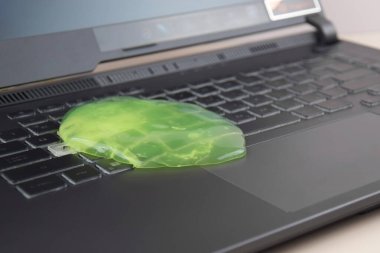 Kharkiv, Ukrayna, 11 Temmuz 2023: Laptop klavyesinde toz temizlemek için yeşil yumuşak temizlik jeli Rog Asus. Bilgisayar klavyeni temizleme konsepti. Ofis temizliği.