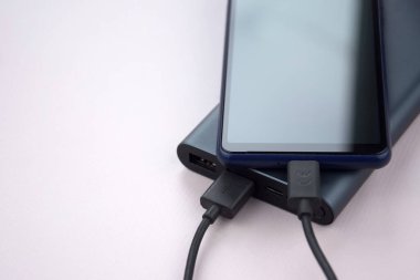 Mobil cihazları şarj etmek için güç bankası. Güç bankası olan siyah akıllı telefon şarj aleti. Mobil aygıtlar için dış pil.