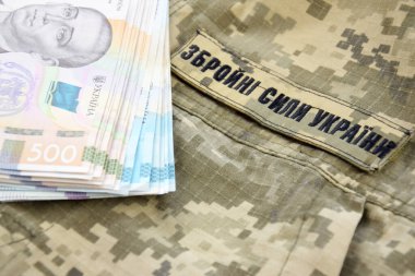Ukrayna hrivnisi, Ukrayna silahlı kuvvetlerinin yazılı olduğu askeri bir pikselin arka planına karşı. Ücret, ödeme ve orduya bağış kavramı..