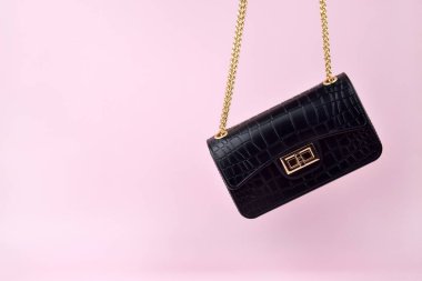 Pembe arka planda siyah kadın çantası, minimalist. Zarif kadın çantası..