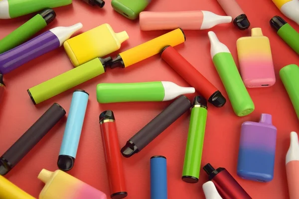 Stock image Set of multicolor disposable electronic cigarettes on a red background. The concept of modern smoking, vaping and nicotine.