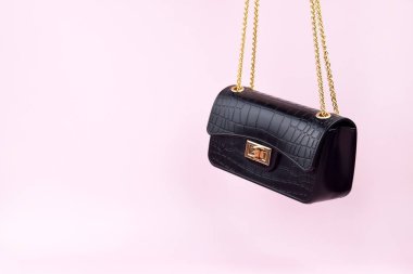 Pembe arka planda siyah kadın çantası, minimalist. Zarif kadın çantası..