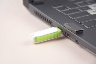 Açık bir dizüstü bilgisayarın klavyesinde beyaz-yeşil USB bellek ya da flash disk.