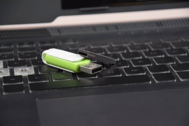 Açık bir dizüstü bilgisayarın klavyesinde beyaz-yeşil USB bellek ya da flash disk.