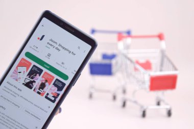 Kharkiv, Ukrayna, 31 Mart 2023: Akıllı telefonlu alışveriş arabası pembe arka planda Joom logosunu açtı.