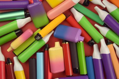 Kırmızı arka planda tek kullanımlık elektronik sigara seti. Modern sigara, buhar ve nikotin konsepti.