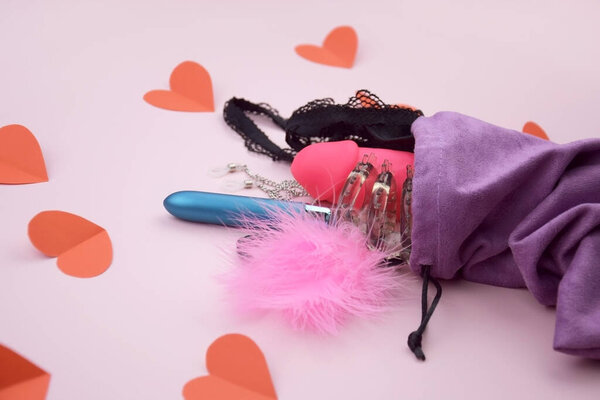 Секс-игрушки в фиолетовой сумке на светлом фоне с текстом копирайта для секс-шопа. Концепция сексуального здоровья.
