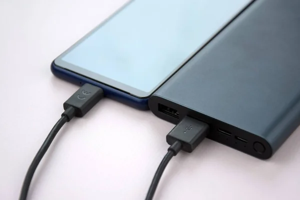 Power bank for charging mobile devices. Black smart phone charger with power bank. External battery for mobile devices.