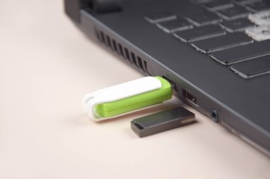 Açık bir dizüstü bilgisayarın klavyesinde beyaz-yeşil USB bellek ya da flash disk.