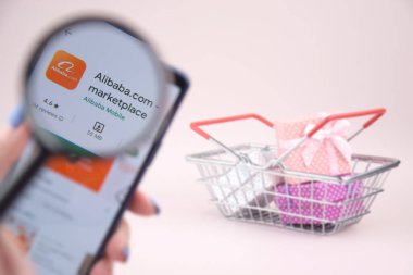 Kharkiv, Ukrayna, 31 Mart 2023: Akıllı telefonlu alışveriş arabası pembe arka planda Alibaba logosu açtı.