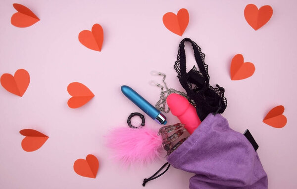 Секс-игрушки в фиолетовой сумке на светлом фоне с текстом копирайта для секс-шопа. Концепция сексуального здоровья.