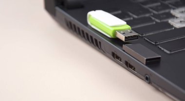 Açık bir dizüstü bilgisayarın klavyesinde beyaz-yeşil USB bellek ya da flash disk.
