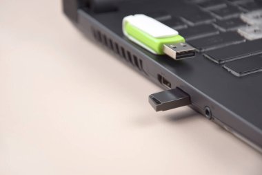 Açık bir dizüstü bilgisayarın klavyesinde beyaz-yeşil USB bellek ya da flash disk.