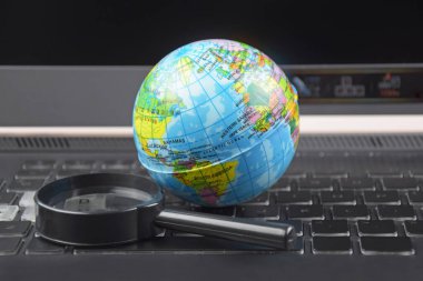 Üzerinde dünya küresi olan dizüstü bilgisayar klavyesi. İnternet 'te bilgi arama kavramı.