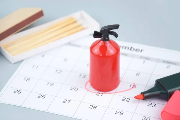 Fire extinguisher and matches on the background of the calendar. Concept of fire extinguisher training class schedule in organization, office, factory, school, etc.