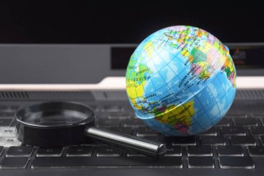 Üzerinde dünya küresi olan dizüstü bilgisayar klavyesi. İnternet 'te bilgi arama kavramı.