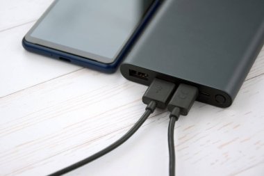 Mobil cihazları şarj etmek için güç bankası. Güç bankası olan siyah akıllı telefon şarj aleti. Mobil aygıtlar için dış pil.
