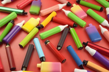 Kırmızı arka planda tek kullanımlık elektronik sigara seti. Modern sigara, buhar ve nikotin konsepti.