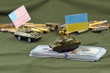Amerikan dolarlarının arka planında Ukrayna bayrağı olan bir savaş tankı. Birleşik Devletler 'den askeri yardım kavramı.